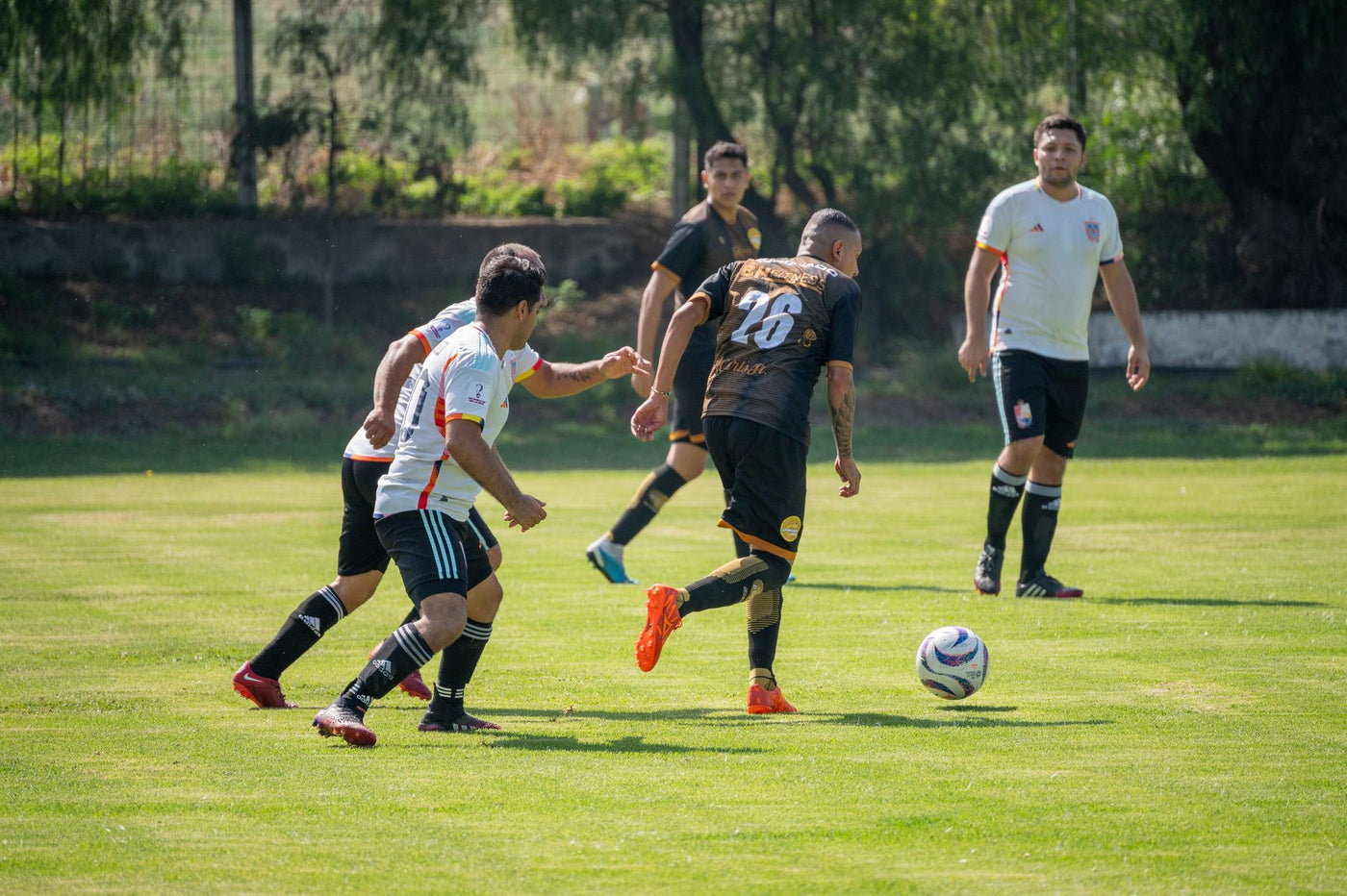 Group of amateur soccer players in a competitive match on a sunny day.